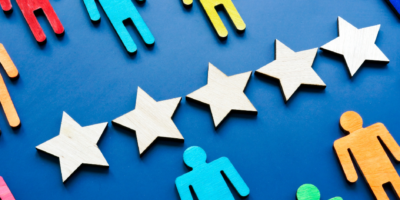 Five white wooden stars on a blue background and wooden figures representing hiring exceptional healthcare leaders